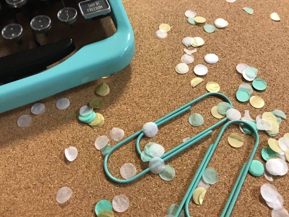 Scattered pastel sea shell beads and blue hair clips on a corkboard.